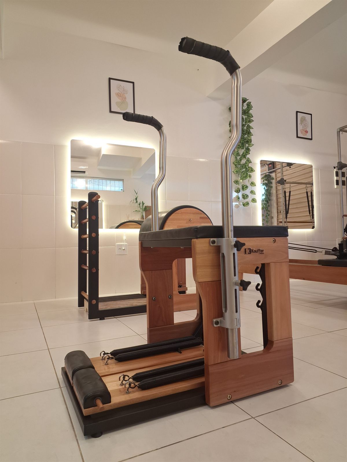 Aparelho Wunda Chair de madeira e metal ao lado de uma escada de Pilates
