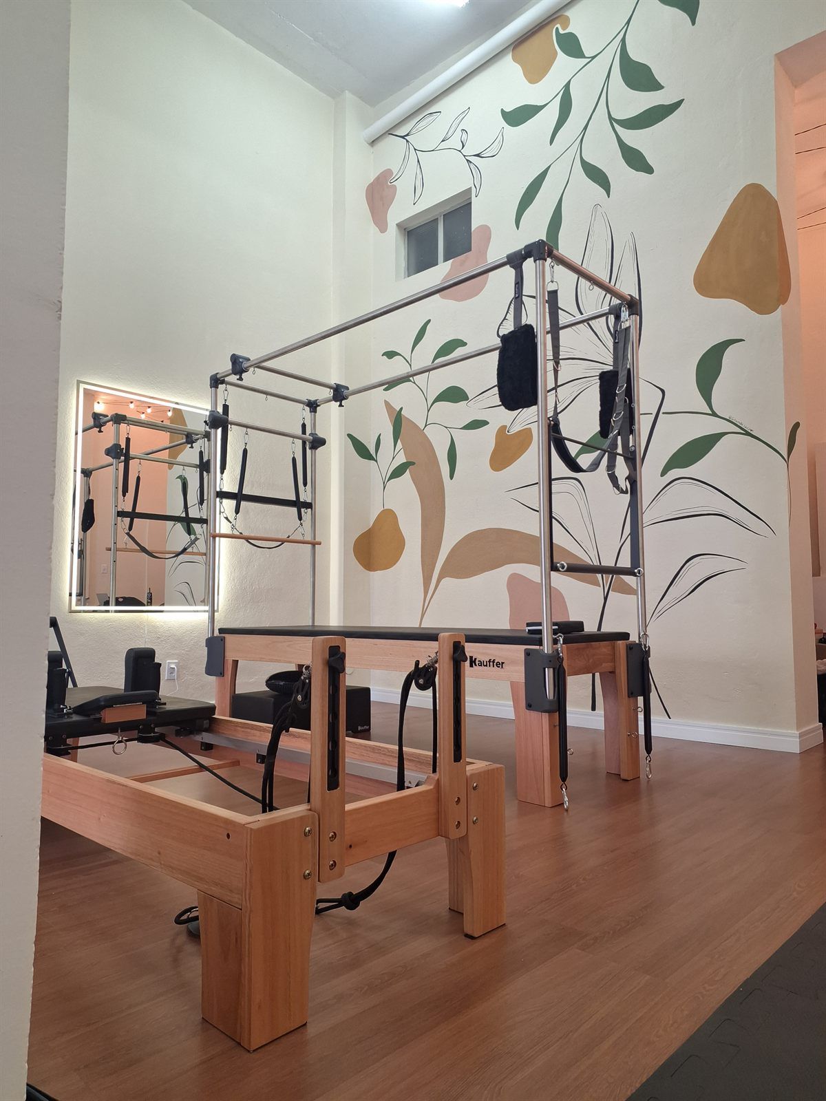 Cadillac e Reformer em sala com mural de folhas na parede