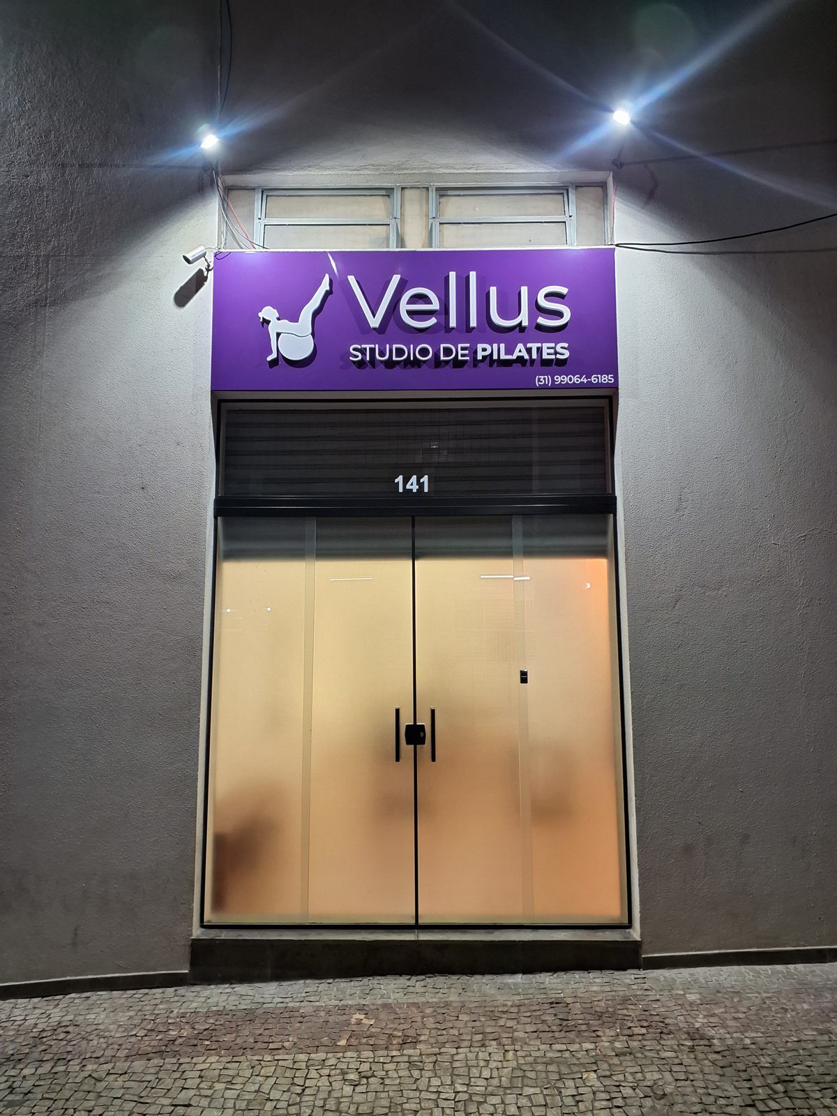 Entrada da unidade Santa Efigênia com a placa roxa da Vellus Studio de Pilates